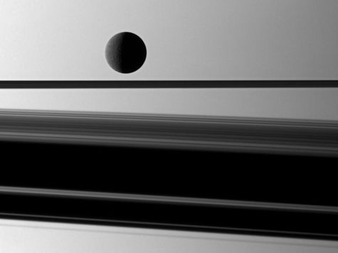 image of Saturn moon rhea and shadows cast by the planet's rings