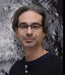 Man with medium length dark/graying hair and glasses