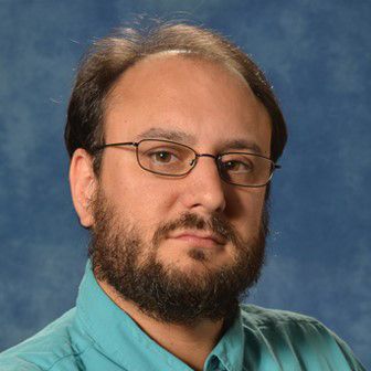 Man with dark hair, beard and glasses