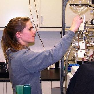 Woman with long brown hair pulled into a ponytail working with lab equipment