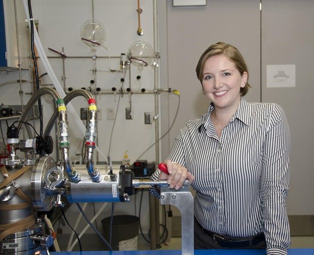 A woman with short light brown hair posing in front of a piece of lab equipment