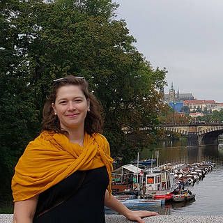 Photo of Mariel Friberg on the bridge connecting to the Žofín Palace, the cultural hear of Prague in the Czech Republic, with a view of the Legion Bridge behind her.