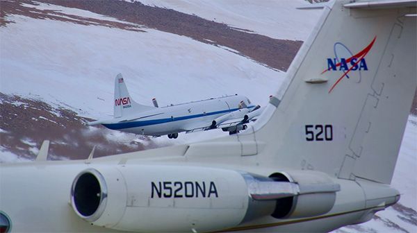 Photo of two NASA aircraft flying over snowy landscape